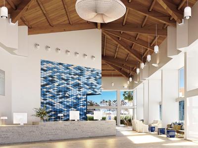 Spacious hotel lobby with high wooden ceiling, blue mosaic wall, and large windows for natural light.