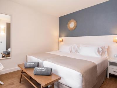 Modern hotel room with large bed, dark blue wall, and wooden furniture.