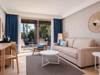Bright living room with sofa, blue curtains, and terrace overlooking garden.