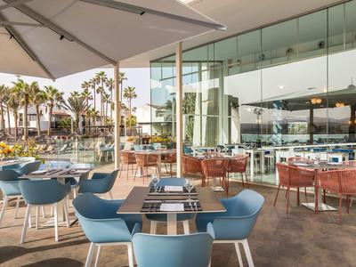Modern outdoor café area with blue and red chairs, tables, and umbrellas.