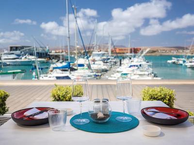 View of a harbor with sailboats from a set table with bowls and glasses.