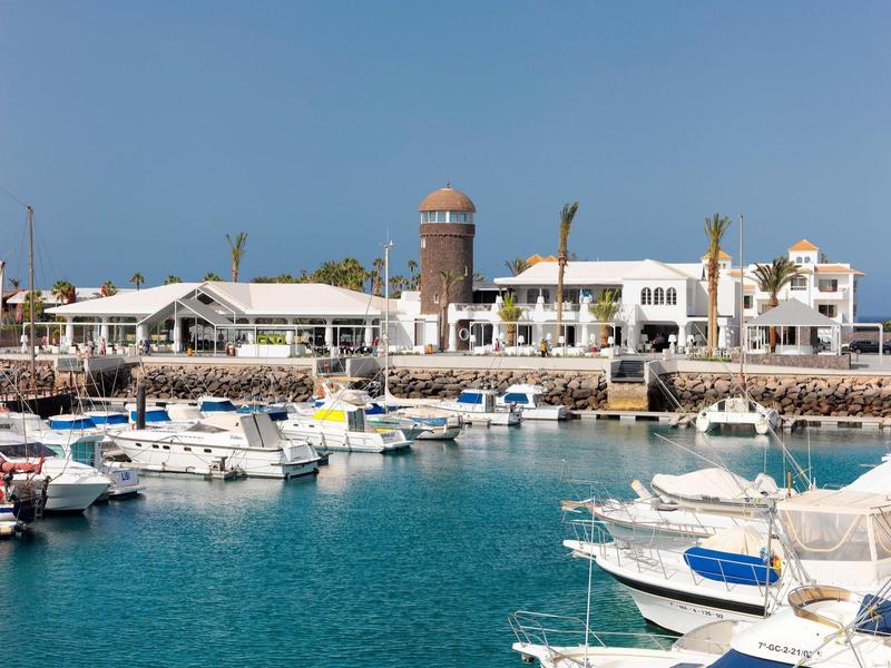 Marina with boats and white buildings under clear sky.
