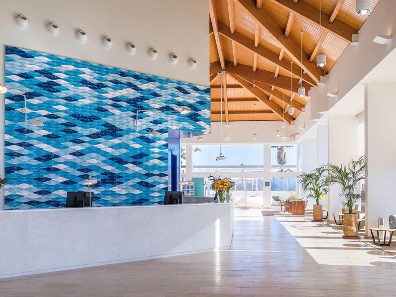 Bright hotel lobby with modern reception and blue wave-patterned wall.