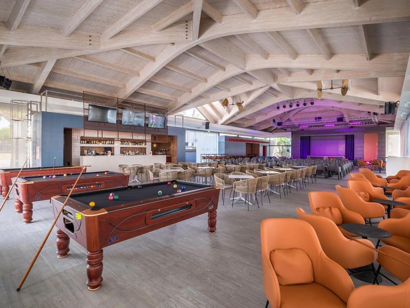 Large event space with pool tables and orange armchairs.