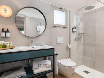 Modernes Badezimmer mit runder Spiegel, Dusche, Toilette und Waschbecken mit minimalistischem Design.