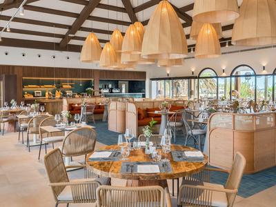 Modernes Restaurant mit eleganten Holzmöbeln und großen Lampenschirmen an der Decke.