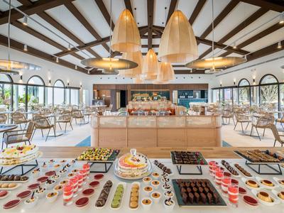 Innenraum eines modernen Restaurants mit Buffet, Holzbalken und großen Fenstern