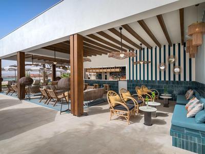 Moderner Außenbereich eines Hotels mit Lounge-Sitzgruppen und Holzdetails unter offenem Himmel.