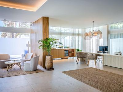 Heller, moderner Wohnbereich mit Sesseln, Teppichen, Pflanze und einer Essgruppe mit großen Fenstern.