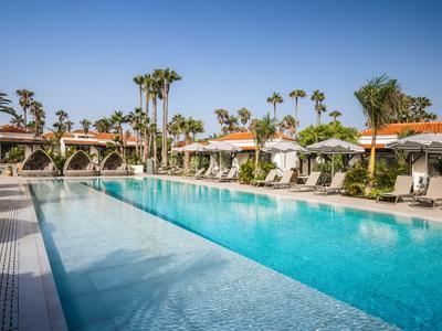 Großer Außenpool mit Liegestühlen und Palmen in einem sonnigen Hotelresort