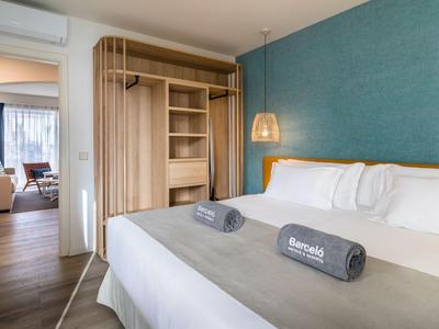 Modernes Schlafzimmer mit Doppelbett, blauer Akzentwand und Holzmöbeln in einer Hotelwohnung.