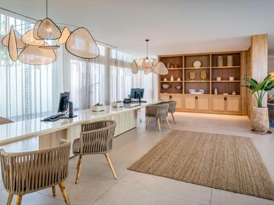 Área de recepción moderna con mostradores blancos, sillas y estantes de madera en una habitación luminosa.