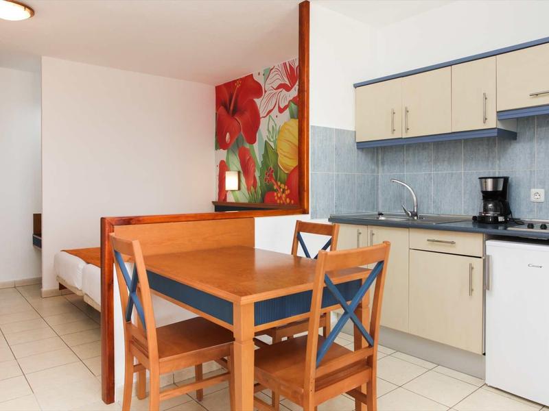 Small kitchen with dining table and bench seating in a compact hotel room.