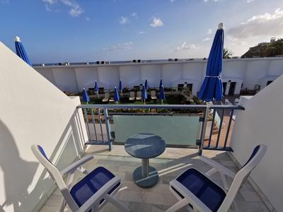 Quiet outdoor seating area with blue chairs and large blue umbrellas by a pool.