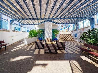 Zadaszony teren na zewnątrz z ławkami i roślinami w hotelu lub ośrodku wypoczynkowym.