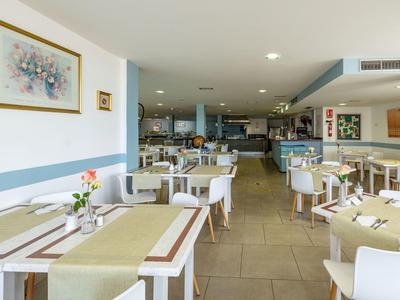 Ristorante luminoso e moderno con tavoli e sedie bianchi e decorazioni sui tavoli.