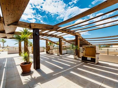 Terrazza sul tetto con pergolato in legno, piante e vista sul cielo blu.