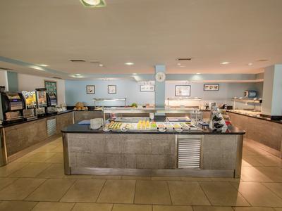 Area buffet con varie postazioni di cibo in una stanza luminosa e spaziosa.