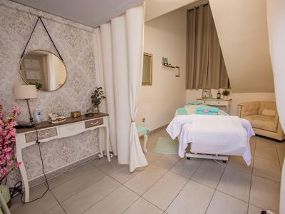 Modern ingerichte behandelruimte met massagetafel en decoratieve spiegel.