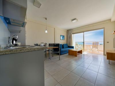 Moderne woonruimte met kitchenette, eettafel, bank en toegang tot balkon met zeezicht.