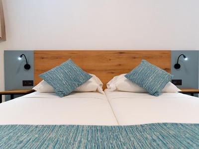 Modernes Doppelbett mit blau gemusterten Kissen und Leselampen an Holzkopfteil