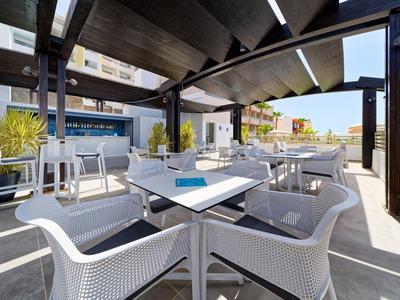 Moderne buitenruimte van een hotel met witte stoelen en tafels onder een overdekt paviljoen.