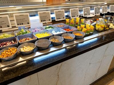 Buffet met verschillende salades en fruit in kommen op een lange toonbank.