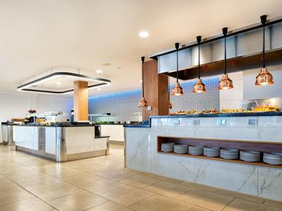 Moderne hotel eetzaal met buffetgedeelte en warme hanglampverlichting.