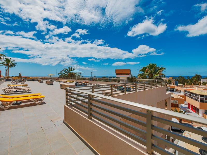 Terrazza sul tetto con lettini, vista su edifici e cielo nuvoloso