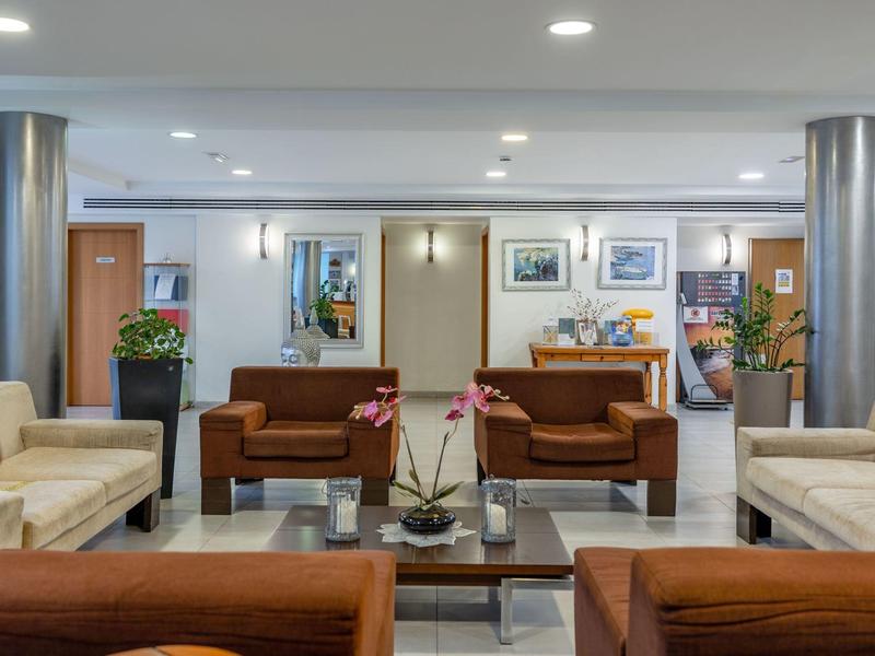 Hall d'hotel moderna con divani, tavoli e un'illuminazione chiara.