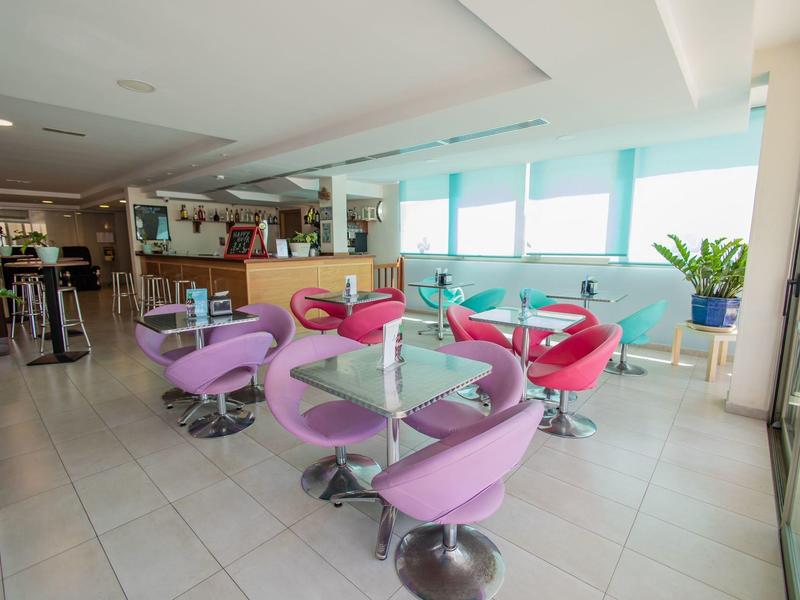 Area bar dell'hotel moderna con poltrone colorate e grandi finestre con luce naturale.