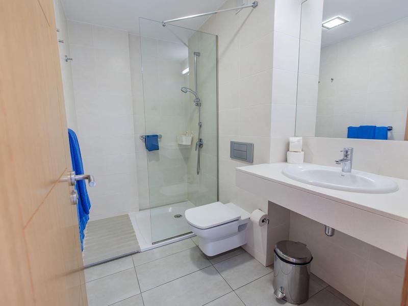 Bagno moderno con doccia, WC, lavabo e grande specchio in colori neutri