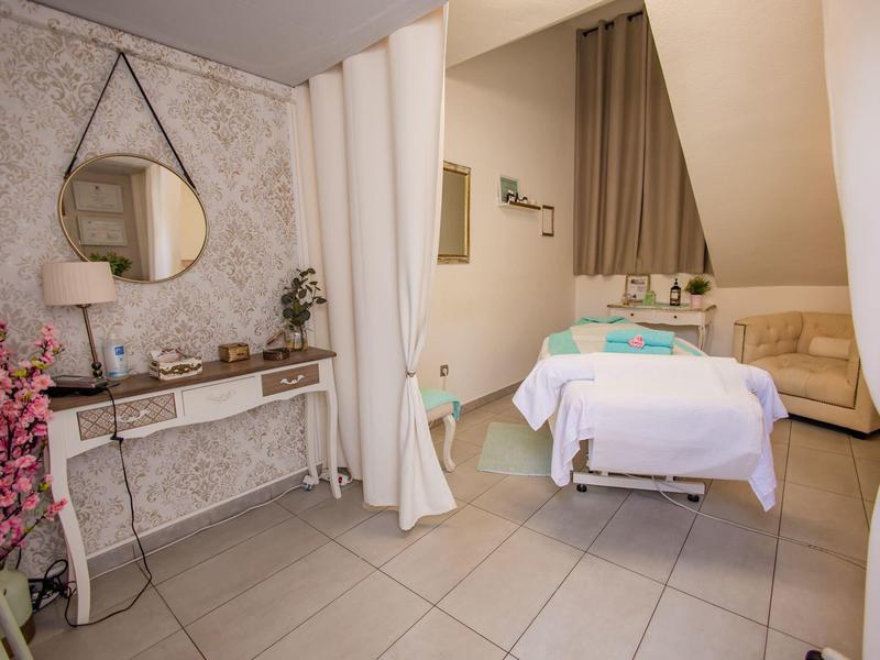 Sala trattamenti con lettino da massaggio, specchio ed elementi decorativi in un hotel benessere.