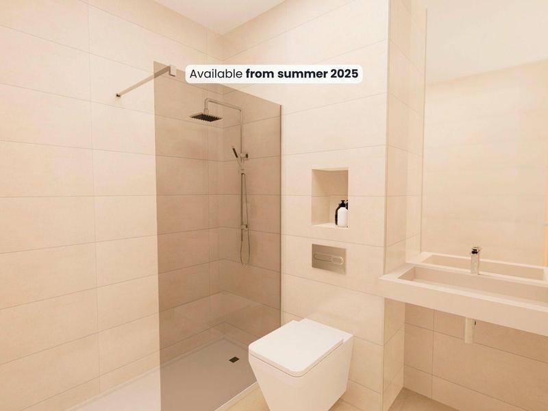 Bagno moderno con doccia a filo pavimento, WC e lavabo in tonalità chiare.