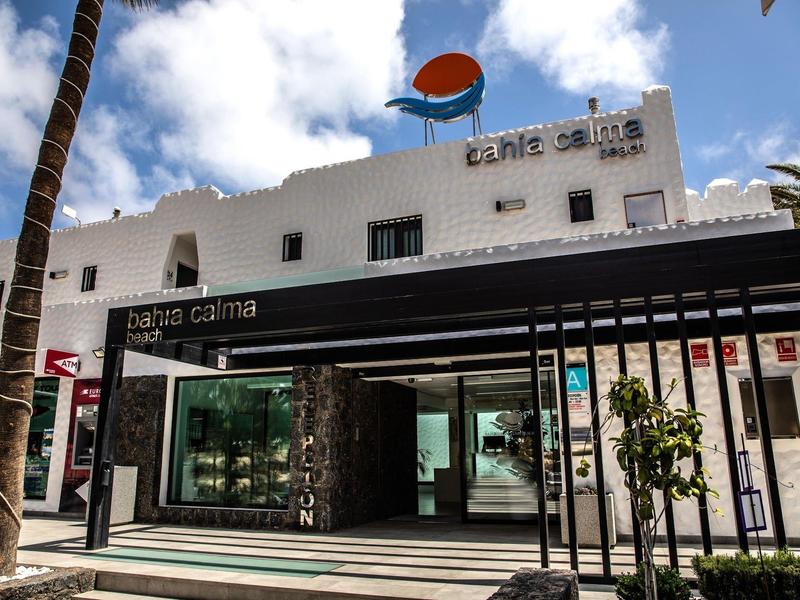 Edificio di hotel moderno con facciata bianca, ingresso in vetro e insegna dell'hotel alla luce del giorno.