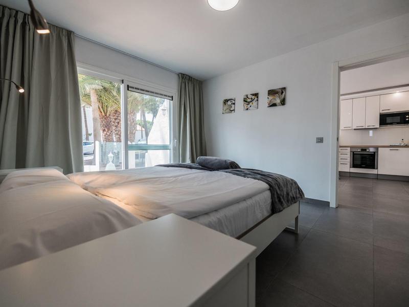 Camera d'hotel moderna con due letti singoli, tende grigie e accesso al balcone.