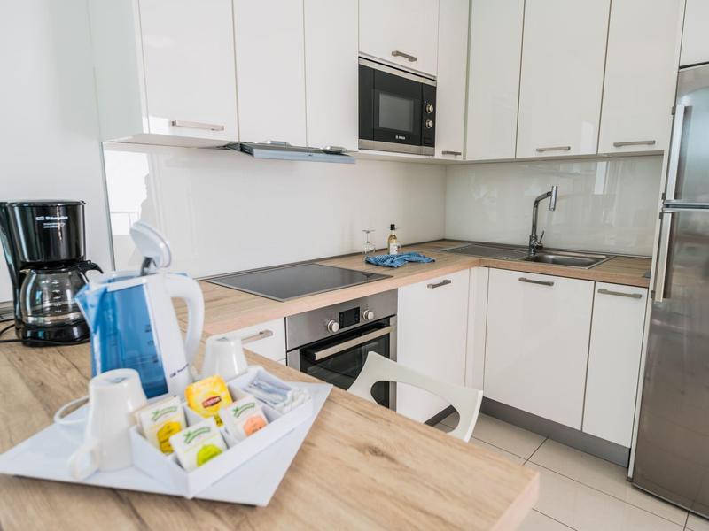 Cucina moderna con armadietti bianchi, macchina per il caffè e vassoio con tazze e tè.