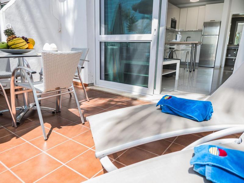 Terrazza soleggiata con lettini e vista su una cucina moderna.