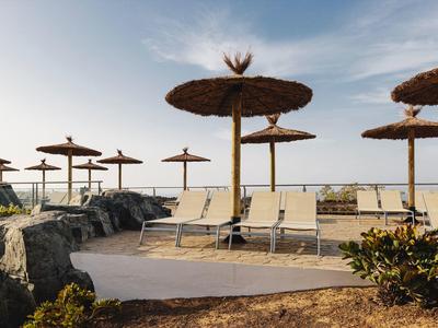 Beach chairs under straw umbrellas on a sunny day by the sea.