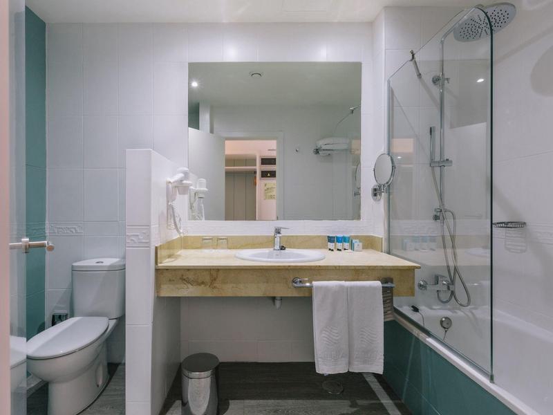 Modern bathroom with marble sink, bathtub, and toilet in a hotel room.