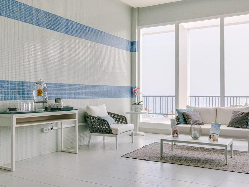 Modern, bright balcony seating area with white furniture and blue striped walls.