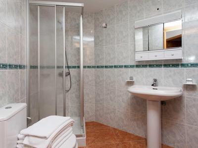 Small bathroom with shower cabin, sink, toilet, and white towels.