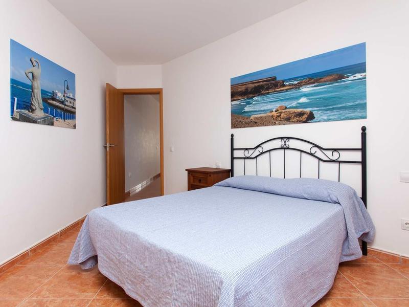 A simply furnished bedroom with a double bed, nightstand, and maritime pictures on the walls.