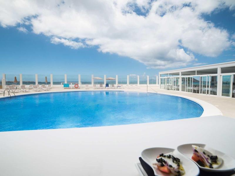 Grande piscina sulla terrazza dell'hotel con vista sul mare e cielo nuvoloso.