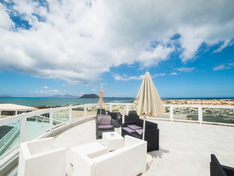 Terrazza sul tetto con zona salotto vista città e mare sotto cielo nuvoloso.