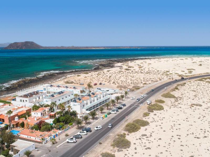 Vista di un resort sul mare con dune di sabbia e una strada in primo piano.