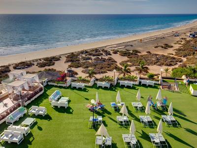 Vista di un giardino dell'hotel con lettini vista mare e spiaggia.