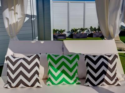 Tre cuscini decorativi con motivo a zigzag su un divano bianco all'aperto.