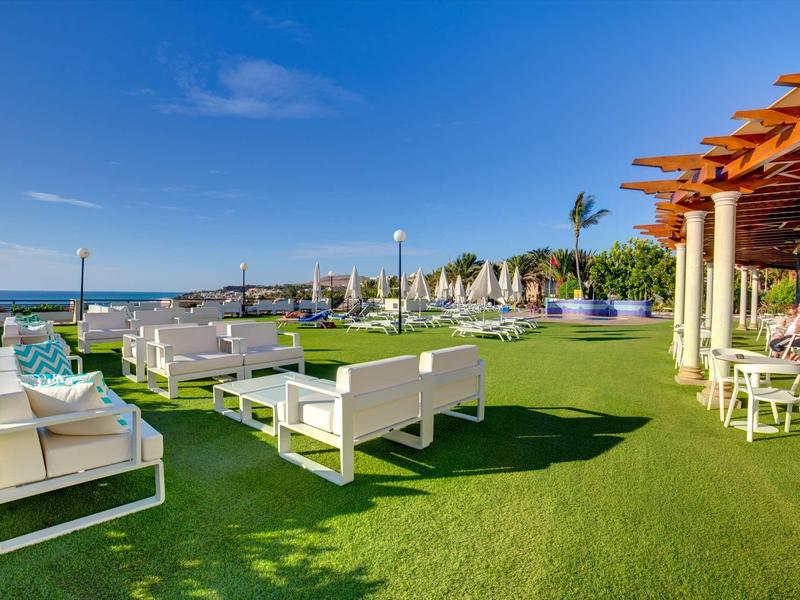 Terrazza esterna con mobili bianchi e vista mare in una giornata di sole.