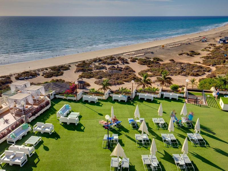 Vista di un giardino dell'hotel con lettini vista mare e spiaggia.